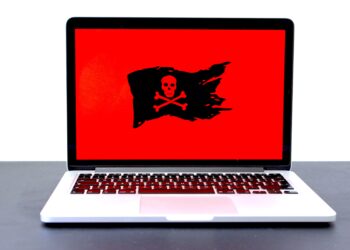 Laptop screen displays a red background with a black skull and crossbones pirate flag; ransomware attack. - Supply Chain News