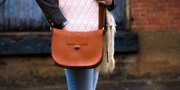 Woman with brown leather crossbody bag, featuring a quilted cream interior. - Supply Chain News