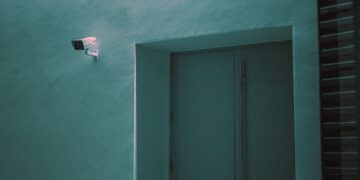 Security camera and exit sign in a modern building, reflecting new German surveillance legislation. - Supply Chain News