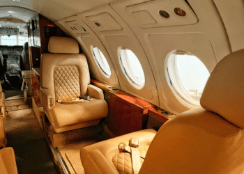 Luxurious private jet cabin interior with tan leather seats and large oval windows. Experience the evolution of luxury air travel. - Supply Chain News