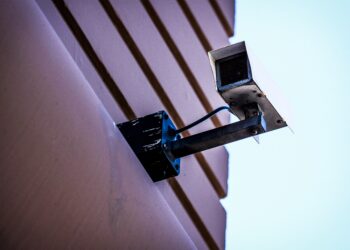 Security camera mounted on building exterior. Enhanced supply chain security. - Supply Chain News