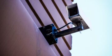 Security camera mounted on building exterior. Enhanced supply chain security. - Supply Chain News