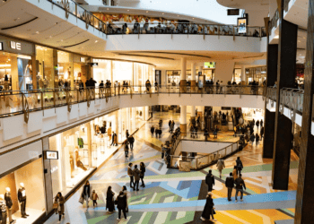 Modern luxury shopping mall interior with shoppers browsing high-end retail stores. - Supply Chain News