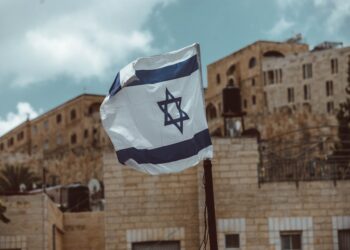 Israeli flag waving in front of Jerusalem buildings. - Supply Chain News