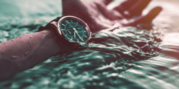 A person's hand with a luxurious watch submerged in transparent water.