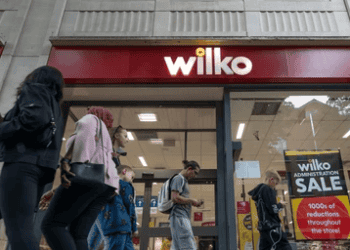 A group of people walk past a Wilko store.