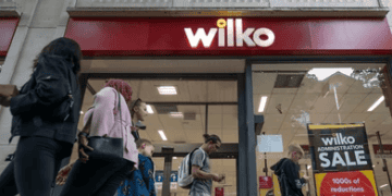 A group of people walk past a Wilko store.