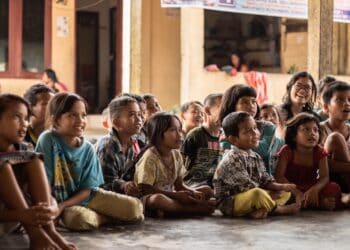 Group of children attentively listening to a speaker, possibly related to human rights discussions. - Supply Chain News