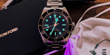 A tom ford watch and other accessories are showcased on a table in the luxury goods industry.