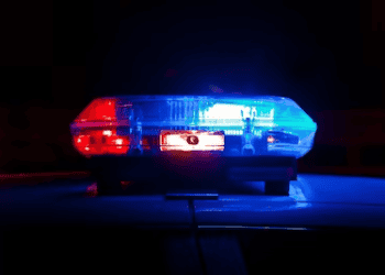 Police car with flashing blue and red lights at night. EU counterfeit operation. - Supply Chain News