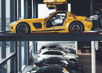 Yellow Mercedes-Benz SLS AMG gullwing car on a car lift above other Mercedes-Benz vehicles. - Supply Chain News