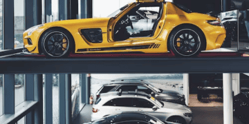 Yellow Mercedes-Benz SLS AMG gullwing car on a car lift above other Mercedes-Benz vehicles. - Supply Chain News