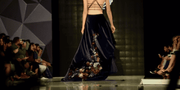 Model showcasing a high-fashion gown at a runway show. The dress features floral embroidery. - Supply Chain News