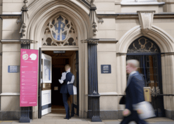 A man in a suit walks out of a building, possibly indicating his affiliation with the Bank of England.