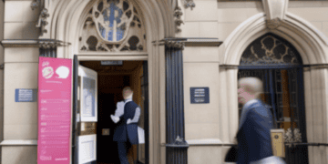 A man in a suit walks out of a building, possibly indicating his affiliation with the Bank of England.