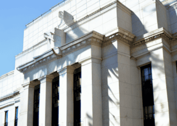 A white building with a clock on it, representing the U.S. Federal Reserve.