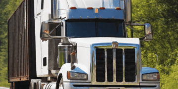 White semi-truck hauling a cargo container on a highway. - Supply Chain News