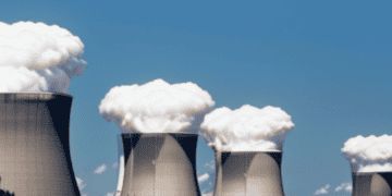 A group of cooling towers emitting smoke as global output from nuclear power declines.