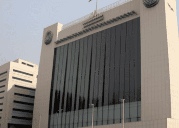 Nigeria's Central Bank, led by Emefiele, stands as a large white building with a flag on it.
