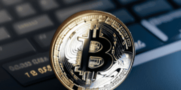 A bitcoin, the digital asset, sits on top of a laptop keyboard in the office of Coinbase's CEO.