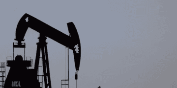 Two oil pumps in the middle of the desert extracting oil amidst an IEA forecast of a weekly increase in oil prices.