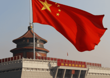 A Chinese flag flies proudly in front of a building, symbolizing the resilience of China amidst US action and potential sanctions.