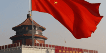 A Chinese flag flies proudly in front of a building, symbolizing the resilience of China amidst US action and potential sanctions.