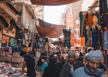 Busy Egyptian market street scene under striped awnings. People shop for clothing and goods. - Supply Chain News