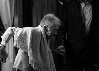 A black and white photo of an older woman holding a man's hand, representing the significance of Economic Opportunity for the Global Aging Population.