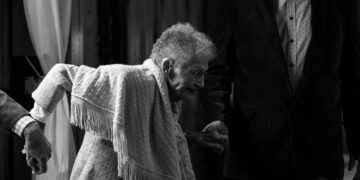 A black and white photo of an older woman holding a man's hand, representing the significance of Economic Opportunity for the Global Aging Population.