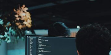 A group of people working on computers in an office, potentially vulnerable to cyberattacks.