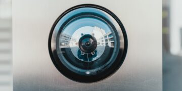 Security camera lens reflecting building exterior. Okta CEO addresses security enhancements. - Supply Chain News