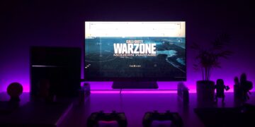 Gaming setup with Call of Duty Warzone displayed on a monitor; purple LED lighting. - Supply Chain News