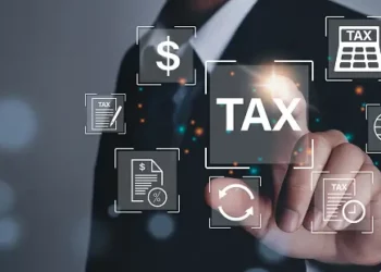 A businessman is pointing at tax icons on a digital screen.