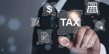 A businessman is pointing at tax icons on a digital screen.