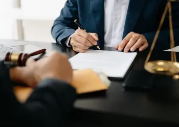 A lawyer signing a document at a desk related to a Coinbase lawsuit.