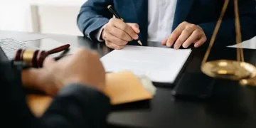 A lawyer signing a document at a desk related to a Coinbase lawsuit.