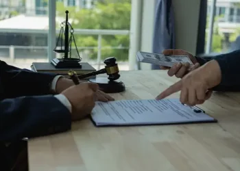 Two men in suits are signing papers at a table, possibly involved in a Singapore Anti-Corruption Agency investigation.