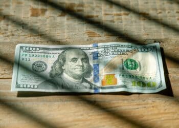 A one hundred dollar bill on a wooden table, representing US Federal Reserve Rate Cuts.