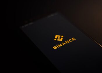 The Binance logo is displayed on a smartphone, highlighting its association with Binance.US.
