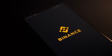 The Binance logo is displayed on a smartphone, highlighting its association with Binance.US.