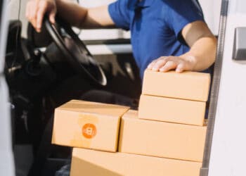 A man sitting in the driver's seat of a Pitney Bowes delivery truck.