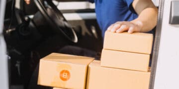 A man sitting in the driver's seat of a Pitney Bowes delivery truck.