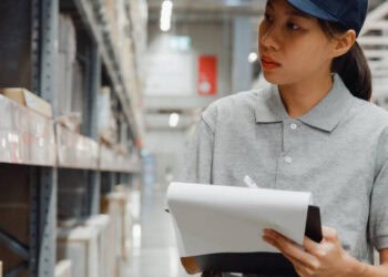 Asian warehouse worker managing inventory balances in a warehouse.