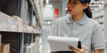 Asian warehouse worker managing inventory balances in a warehouse.