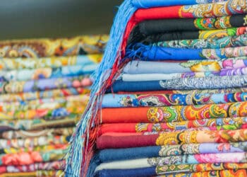 A pile of colorful scarves on a table, representing the plight of Bangladesh Garment Workers in the Fair Wage Movement.