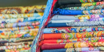 A pile of colorful scarves on a table, representing the plight of Bangladesh Garment Workers in the Fair Wage Movement.