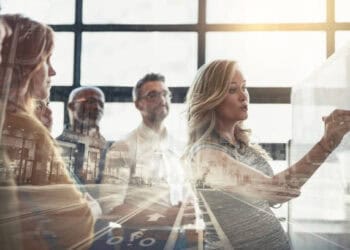 The Chief Supply Chain and Operations Officer of Perdue Foods leading a group of business people in an engaging discussion, while looking at a whiteboard.