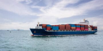 A large container ship sailing in the ocean, carrying cargo volumes bound for the Port of Oakland.