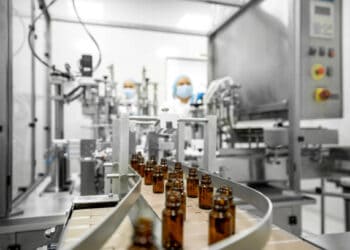 A line of bottles on a conveyor belt in a factory, addressing drug shortages and aiding domestic production regulated by the U.S. government.